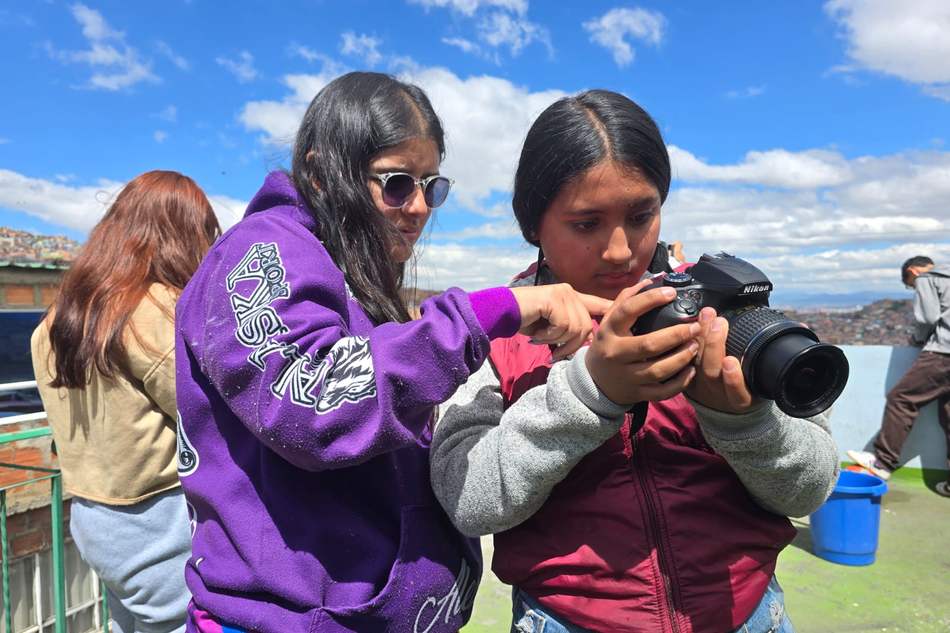 Dos jóvenes revisan juntas una cámara en un taller de fotografía de Fundación TAAP